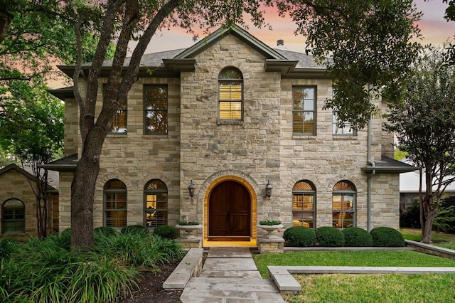 view of front of home with a shingled roof and a yard