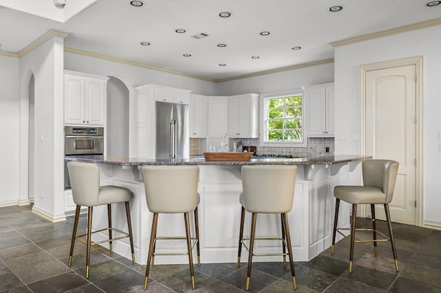 kitchen featuring white cabinets, a kitchen bar, and stainless steel appliances