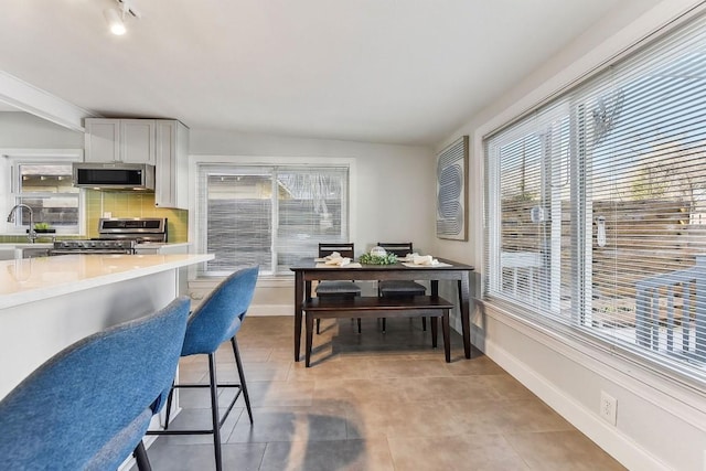 906 E 43rd St, Austin, TX 78751 - kitchen with appliances with stainless steel finishes, light countertops, backsplash, a breakfast bar, and light tile patterned floors