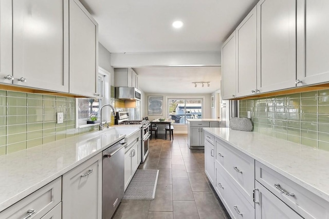 906 E 43rd St, Austin, TX 78751 - kitchen featuring stainless steel appliances, decorative backsplash, light stone countertops, dark tile patterned floors, and recessed lighting