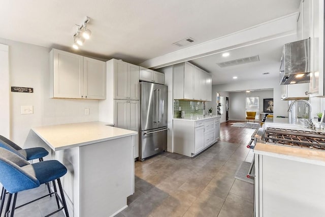 906 E 43rd St, Austin, TX 78751 - kitchen featuring high end fridge, a peninsula, a breakfast bar area, and light countertops