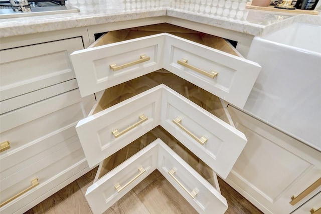 details featuring dark hardwood / wood-style flooring, sink, white cabinetry, and light stone countertops