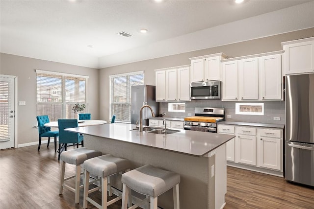 kitchen featuring stainless steel appliances, sink, an island with sink, and white cabinets