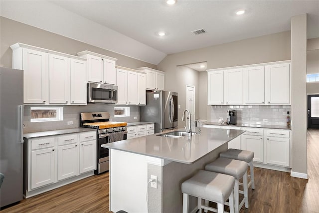 kitchen featuring sink, a breakfast bar, a kitchen island with sink, stainless steel appliances, and white cabinets