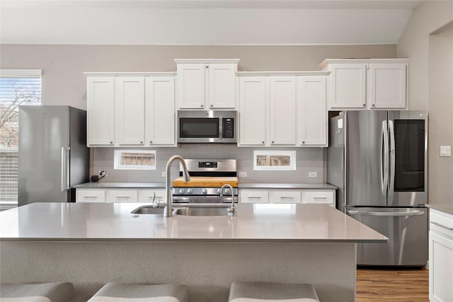 kitchen featuring white cabinetry, appliances with stainless steel finishes, a kitchen island with sink, and sink