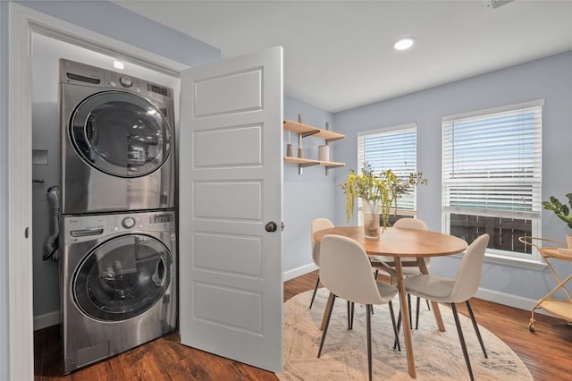 clothes washing area featuring stacked washer / dryer and dark hardwood / wood-style flooring