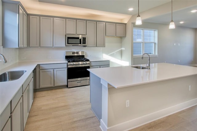 5812 Rotunda Vw, Austin, TX 78747 - kitchen with stainless steel appliances, gray cabinets, tasteful backsplash, a kitchen island with sink, and recessed lighting