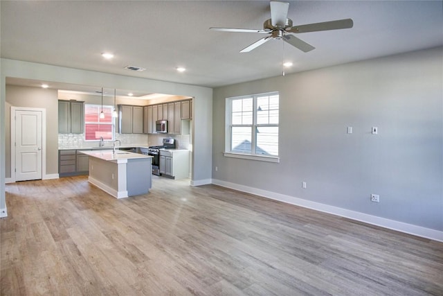 5812 Rotunda Vw, Austin, TX 78747 - kitchen featuring stainless steel appliances, open floor plan, ceiling fan, a kitchen island with sink, and light wood-style flooring