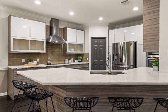 3305 Avenal Dr, Austin, TX 78738 - kitchen with wall chimney range hood, stainless steel appliances, modern cabinets, a kitchen breakfast bar, and crown molding