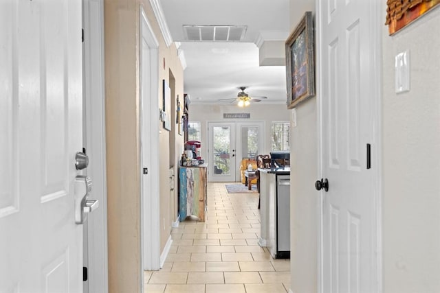 hallway with crown molding, visible vents, baseboards, and light tile patterned floors