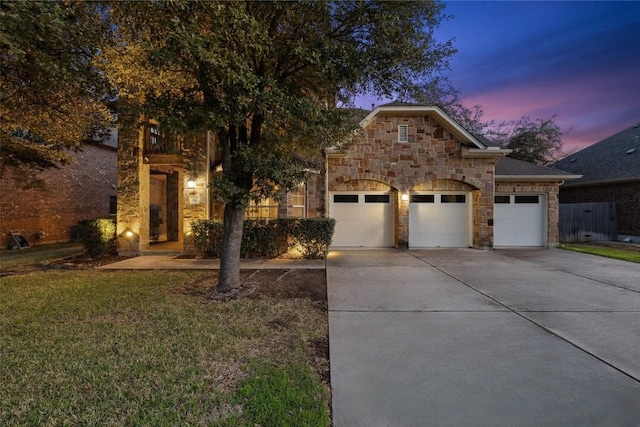 view of front of property featuring a garage, concrete driveway, a front lawn, and stone siding