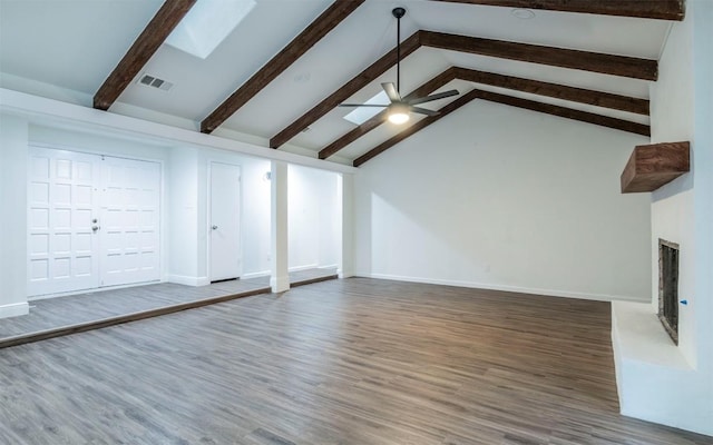 unfurnished living room with dark hardwood / wood-style floors, high vaulted ceiling, a skylight, beamed ceiling, and ceiling fan