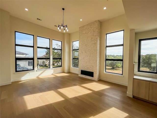 unfurnished living room featuring a wealth of natural light, a fireplace, and light wood-type flooring