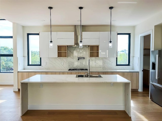 kitchen featuring appliances with stainless steel finishes, white cabinetry, sink, light stone counters, and a center island with sink