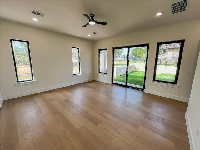 empty room featuring ceiling fan, a healthy amount of sunlight, and light wood-type flooring