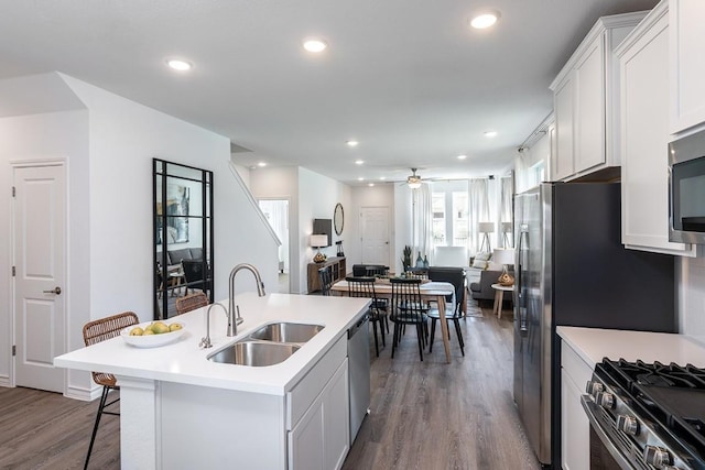 kitchen with sink, a breakfast bar area, appliances with stainless steel finishes, an island with sink, and white cabinets