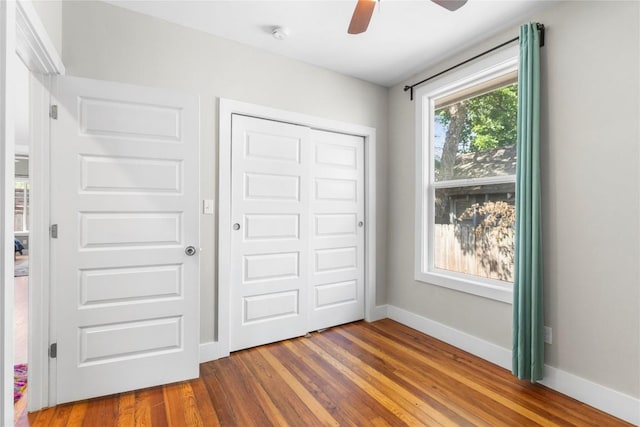 unfurnished bedroom with wood-type flooring, a closet, and ceiling fan