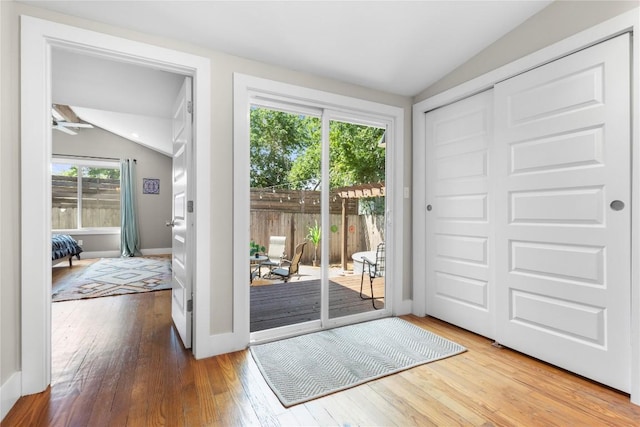 doorway with hardwood / wood-style flooring and vaulted ceiling