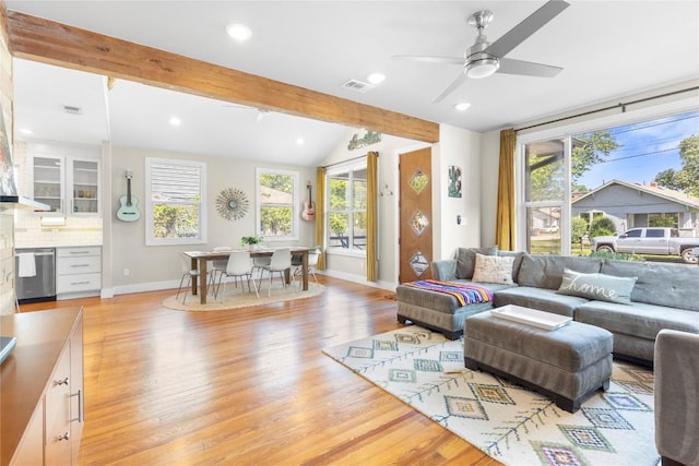 living room featuring vaulted ceiling with beams, a wealth of natural light, and light hardwood / wood-style flooring