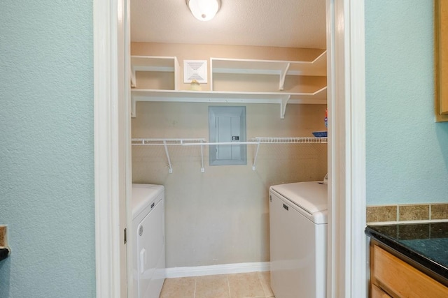 clothes washing area with separate washer and dryer, light tile patterned floors, and electric panel