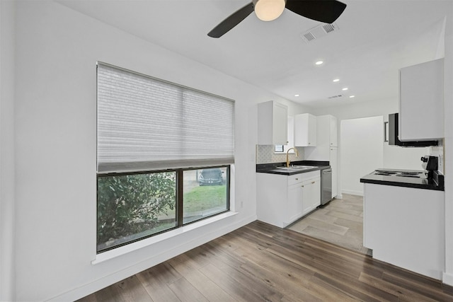 2018 W Rundberg Ln Unit 9D, Austin, TX 78758 - kitchen featuring stainless steel dishwasher, dark countertops, white cabinets, a ceiling fan, and light wood-style flooring