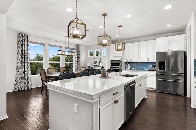 kitchen featuring pendant lighting, sink, appliances with stainless steel finishes, an island with sink, and white cabinets