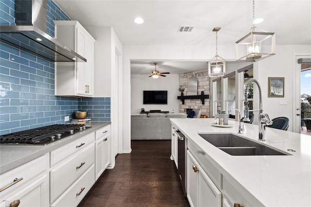 kitchen featuring pendant lighting, ceiling fan, stainless steel appliances, white cabinets, and wall chimney exhaust hood