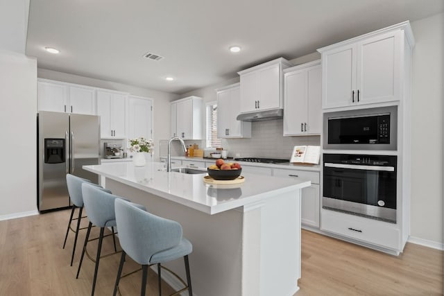 337 Five Mile Creek Way, Kyle, TX 78640 - kitchen featuring appliances with stainless steel finishes, under cabinet range hood, a sink, light wood-type flooring, and recessed lighting