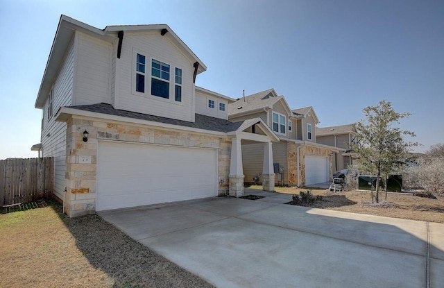 view of front of house featuring concrete driveway, an attached garage, fence, and stone siding