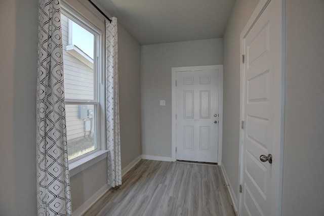 doorway with baseboards and light wood-style flooring