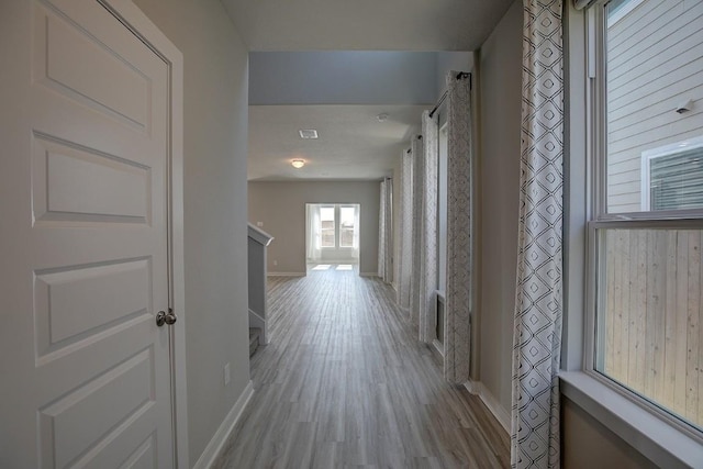 corridor featuring light wood finished floors, visible vents, and baseboards