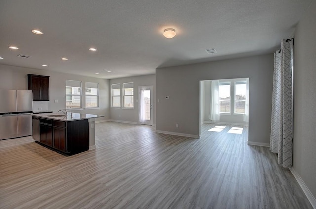 kitchen featuring open floor plan, light wood-style flooring, stainless steel appliances, and a sink