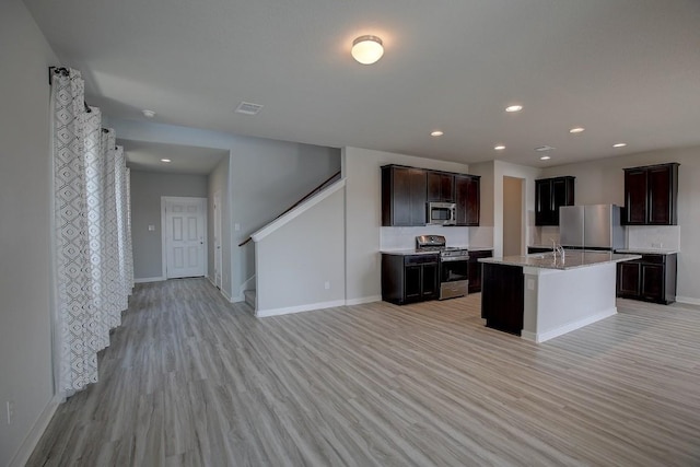 kitchen featuring visible vents, light wood finished floors, dark brown cabinetry, appliances with stainless steel finishes, and open floor plan