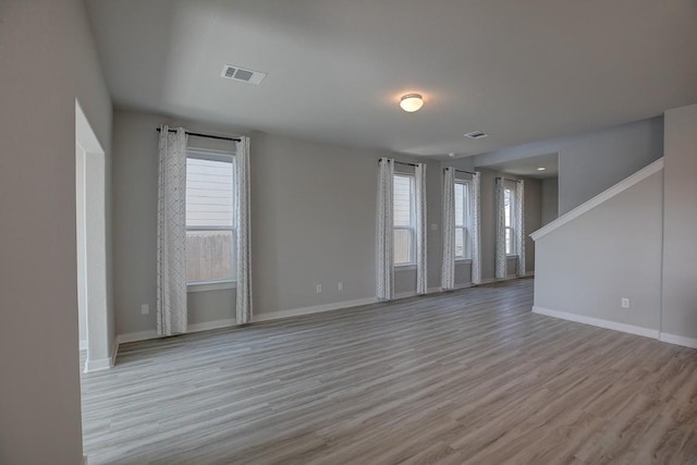 unfurnished living room featuring wood finished floors, visible vents, and baseboards