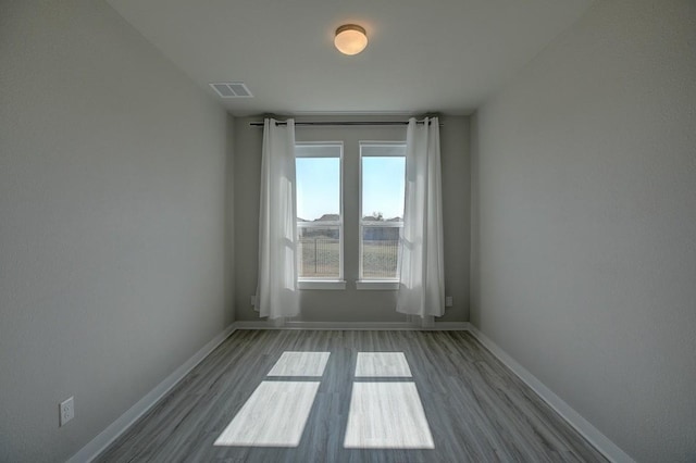 empty room with visible vents, baseboards, and wood finished floors