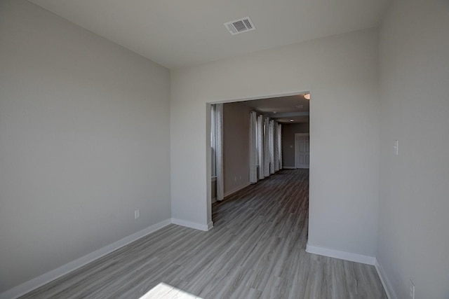 spare room featuring wood finished floors, visible vents, and baseboards