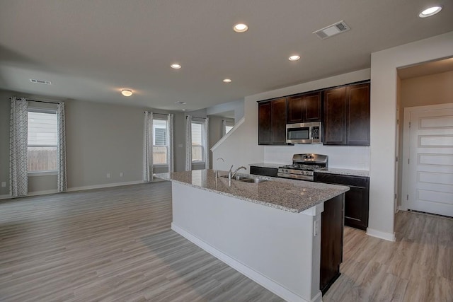 kitchen with light stone counters, visible vents, appliances with stainless steel finishes, and a sink