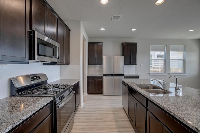 kitchen featuring a sink, stainless steel appliances, light stone countertops, and visible vents