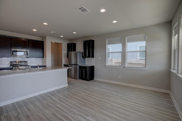 kitchen featuring visible vents, baseboards, appliances with stainless steel finishes, and decorative backsplash