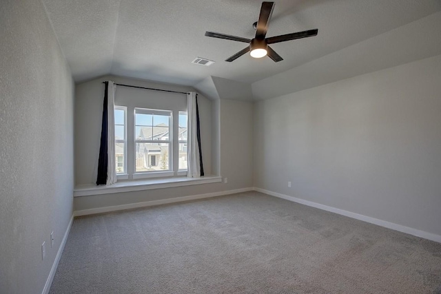 carpeted spare room featuring baseboards, lofted ceiling, a textured ceiling, and visible vents