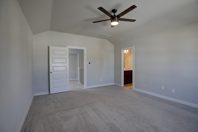 unfurnished bedroom with light carpet, visible vents, baseboards, and lofted ceiling