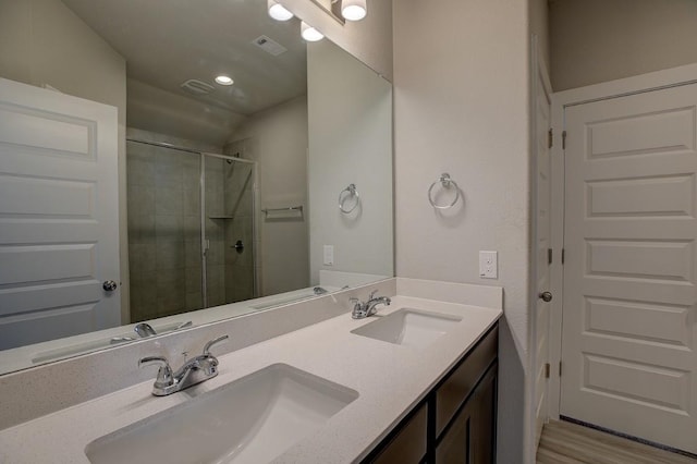 bathroom featuring a sink, visible vents, double vanity, and a shower stall