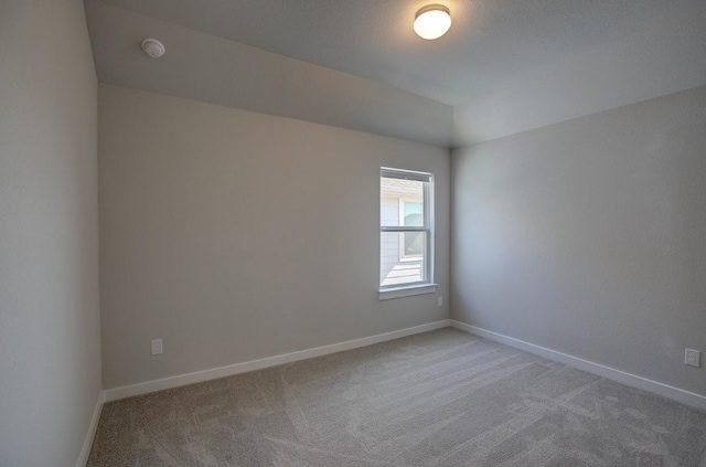 carpeted empty room with lofted ceiling and baseboards