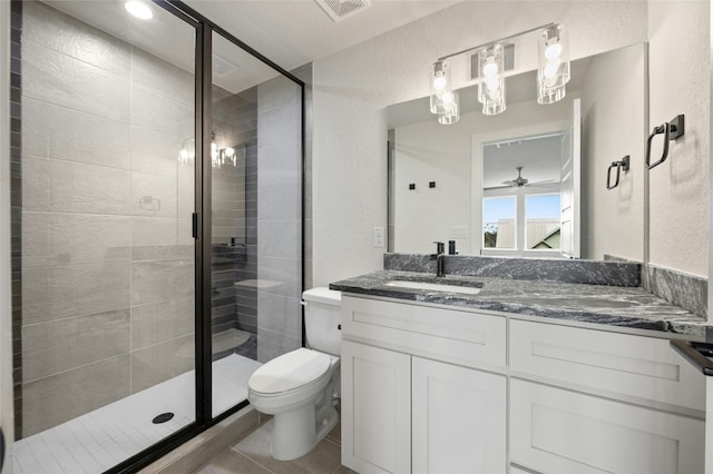 bathroom featuring tile patterned floors, vanity, toilet, and a shower with door