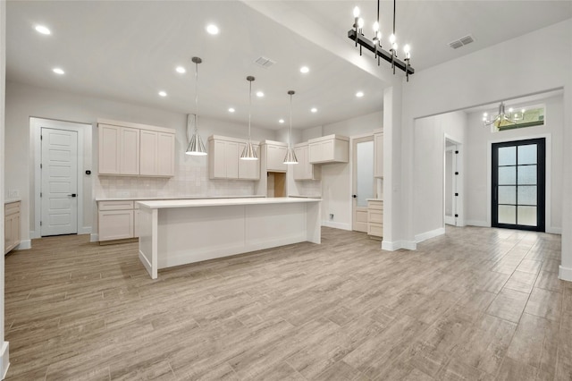 kitchen featuring backsplash, light wood-type flooring, a kitchen island, and white cabinets