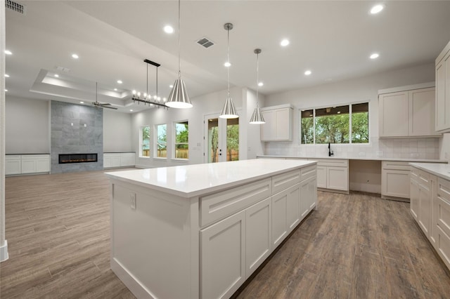 kitchen featuring tasteful backsplash, white cabinetry, hanging light fixtures, hardwood / wood-style flooring, and a center island