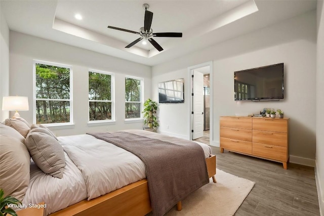 bedroom with a raised ceiling, dark hardwood / wood-style floors, and ceiling fan