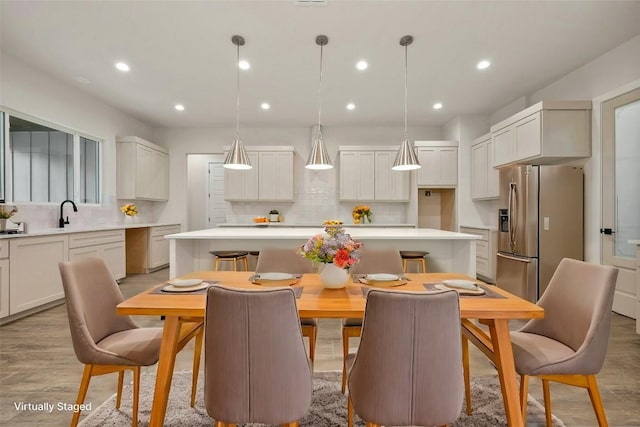 kitchen featuring hanging light fixtures, white cabinetry, a center island, and stainless steel fridge