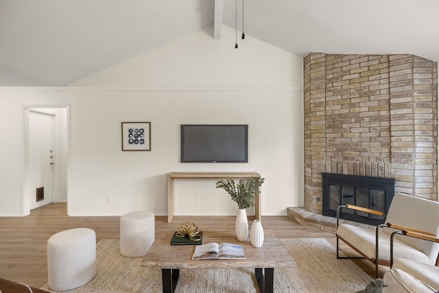 living room with lofted ceiling with beams, wood-type flooring, and a fireplace