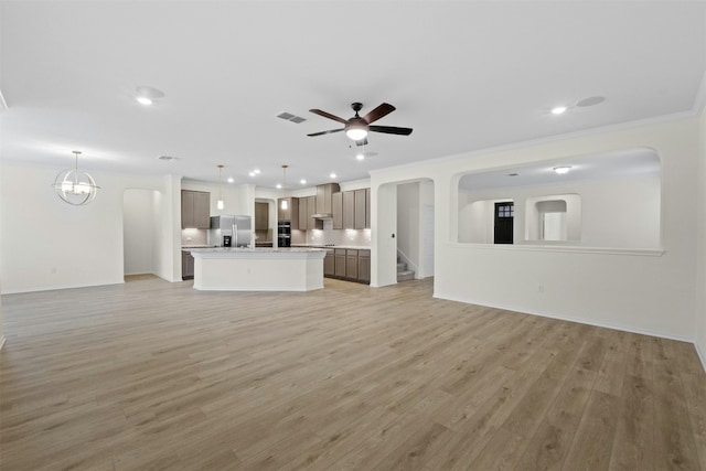 unfurnished living room featuring ornamental molding, ceiling fan with notable chandelier, and light hardwood / wood-style floors